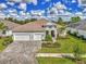 Beautiful home with a tile roof, three-car garage, and a lush lawn with manicured landscaping and brick paver driveway at 12404 Destin Loop, Venice, FL 34293