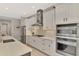 Modern kitchen with stainless appliances and gas range, featuring white cabinetry and large countertops at 12404 Destin Loop, Venice, FL 34293