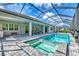 Back view of house with a screened-in pool with a spa, patio with furniture and outdoor kitchen at 12404 Destin Loop, Venice, FL 34293