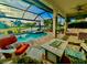Relaxing screened-in lanai with a pool, spa, fire pit, and plenty of seating overlooking the water at 13092 Rinella St, Venice, FL 34293