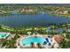 Gorgeous aerial view of the resort-style pool, spa, and surrounding landscaping near the community lake at 13841 Campoleone St, Venice, FL 34293