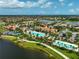 Aerial view of a community featuring swimming pools, palm trees, and luxury homes along a lake at 13841 Campoleone St, Venice, FL 34293