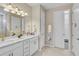 Modern bathroom features double sinks, white cabinetry and a doorway into a walk in closet at 13841 Campoleone St, Venice, FL 34293