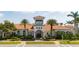 Community clubhouse featuring palm trees, manicured landscaping, and a light terra cotta roof at 13871 Miranese St, Venice, FL 34293