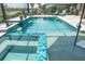 A view of a screened-in pool, with a sun shelf, spa, and rock waterfall feature at 13871 Miranese St, Venice, FL 34293