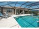 A view of a screened-in pool with an attached patio featuring a dining table and lounge furniture at 13871 Miranese St, Venice, FL 34293