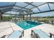 Screened-in pool with a sun shelf, spa, rock waterfall feature, and lake view at 13871 Miranese St, Venice, FL 34293