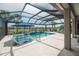 Screened-in pool with a sun shelf, spa, lounge chairs, and view of the lake at 13871 Miranese St, Venice, FL 34293
