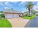 Charming single-story home featuring a well-manicured lawn, tiled roof, palm trees, and a two-car garage at 16 Oakwood N Dr # 16, Englewood, FL 34223