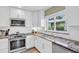 Bright kitchen with stainless appliances, modern backsplash, and light countertops by large window at 16 Oakwood N Dr # 16, Englewood, FL 34223
