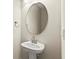 Modern bathroom with a sleek pedestal sink and an oval, frameless mirror at 1607 Laurel Brook Ln, Port Charlotte, FL 33953