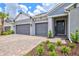 Welcoming home exterior with a three-car garage, manicured landscaping, and a covered entryway at 1607 Laurel Brook Ln, Port Charlotte, FL 33953