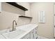 Clean laundry space featuring a white sink, counter, cabinets, and floating shelves at 1607 Laurel Brook Ln, Port Charlotte, FL 33953