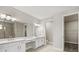 An interior view of the main bathroom featuring double sinks, large mirrors, and a walk-in closet at 1607 Laurel Brook Ln, Port Charlotte, FL 33953