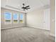 Spacious main bedroom featuring tray ceiling, ceiling fan, carpet, and three windows providing backyard lake views at 1607 Laurel Brook Ln, Port Charlotte, FL 33953