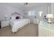 Serene bedroom featuring a queen bed, white wicker furnishings, and soft lilac walls at 168 The Corso # 168, Venice, FL 34285