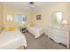 Sunlit bedroom featuring twin beds, a wicker dresser, and neutral carpeting at 168 The Corso # 168, Venice, FL 34285