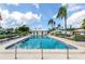 Community pool with crystal clear water, lined with lounge chairs and surrounded by palm trees at 168 The Corso # 168, Venice, FL 34285