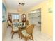 Bright dining area with a glass-top table, stylish rattan chairs and a view of the kitchen at 168 The Corso # 168, Venice, FL 34285