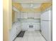 Functional kitchen with white cabinets, a white appliance package, and neutral tile flooring at 168 The Corso # 168, Venice, FL 34285
