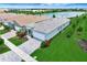 Aerial view of a modern home with a manicured yard and tile roof, in a well-planned community with a lake nearby at 17873 Grand Prosperity Dr, Venice, FL 34293