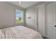 Bright bedroom with a window and closet featuring crisp white paint and light gray wood-look floors at 17873 Grand Prosperity Dr, Venice, FL 34293