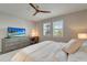 This bright bedroom includes a ceiling fan, dresser with a TV, desk and a view to the outdoors at 17873 Grand Prosperity Dr, Venice, FL 34293
