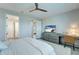 This bedroom has wood-look floors, a ceiling fan, dresser with TV, desk, and white doors at 17873 Grand Prosperity Dr, Venice, FL 34293