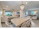 Elegant dining area with a beaded chandelier, flowing into a spacious living room with sliding glass doors at 17873 Grand Prosperity Dr, Venice, FL 34293