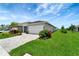 Well-maintained front yard with lush grass, mature landscaping, and a paver driveway at 17873 Grand Prosperity Dr, Venice, FL 34293