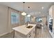 Bright, open kitchen island featuring quartz countertops, a stainless steel sink, and modern pendant lights at 17873 Grand Prosperity Dr, Venice, FL 34293