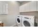 Efficient laundry room with modern washer and dryer, complete with storage cabinets above at 17873 Grand Prosperity Dr, Venice, FL 34293