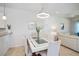 Elegant dining area features a modern chandelier, glass-top table, and views into the living room at 19269 Serafina St, Venice, FL 34293