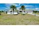 Charming single-story home featuring two palm trees, a green lawn, and a bright white exterior at 20430 Edgewater Dr, Port Charlotte, FL 33952