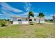 Charming single-story home featuring two palm trees, a green lawn, and a bright white exterior at 20430 Edgewater Dr, Port Charlotte, FL 33952
