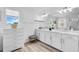 Bright bathroom with double vanity, white cabinets, white marble countertop, and hardwood style floors at 2146 Snapdragon Ln, Venice, FL 34292