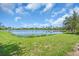 Scenic view of a tranquil lake surrounded by lush green grass and neighborhood homes at 2146 Snapdragon Ln, Venice, FL 34292