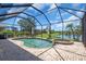 Relaxing outdoor pool and spa area with a screened enclosure overlooking a serene lake at 2146 Snapdragon Ln, Venice, FL 34292
