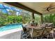 Screened-in patio features a dining table and chairs, offering a lovely view of the pool and lush landscaping at 2944 Oriole Dr, Sarasota, FL 34243