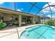 Inviting screened-in pool with a travertine deck, ceiling fans and lush plants for a relaxing outdoor living space at 2944 Oriole Dr, Sarasota, FL 34243