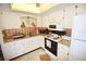 Bright kitchen featuring white cabinets, granite countertops, and copper backsplash at 320 Base E Ave # 215, Venice, FL 34285