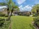 Beautiful backyard with a lush green lawn, tropical landscaping, and a screened-in pool area at 346 Roseling Cir, Venice, FL 34293