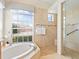 Bright bathroom featuring a soaking tub, separate glass shower, and window with blinds at 355 Swallow Cir, Venice, FL 34285