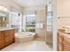 Elegant bathroom featuring a soaking tub, glass-enclosed shower, and dual vanities with granite countertops at 355 Swallow Cir, Venice, FL 34285