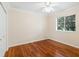 Bedroom with hardwood floors, white trim, a ceiling fan, and a window overlooking the greenery at 355 Swallow Cir, Venice, FL 34285