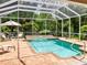 Relaxing screened-in pool and spa area with lounge chairs and tropical landscaping at 355 Swallow Cir, Venice, FL 34285