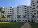 Multi-story condo complex with multiple units, balconies, and palm trees, set in a grassy lawn at 3730 Cadbury Cir # 703, Venice, FL 34293