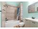 Bathroom with tub and shower, white cabinets, toilet, and horizontal tiling with light teal colored walls at 3863 Albin Ave, North Port, FL 34286