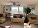 Bright living room with neutral furniture, a ceiling fan, and large windows at 411 Vasto Dr, Venice, FL 34285