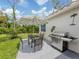 Outdoor patio with dining set and grill, set against a backdrop of lush greenery and a clear sky at 4176 Summertree Rd, Venice, FL 34293
